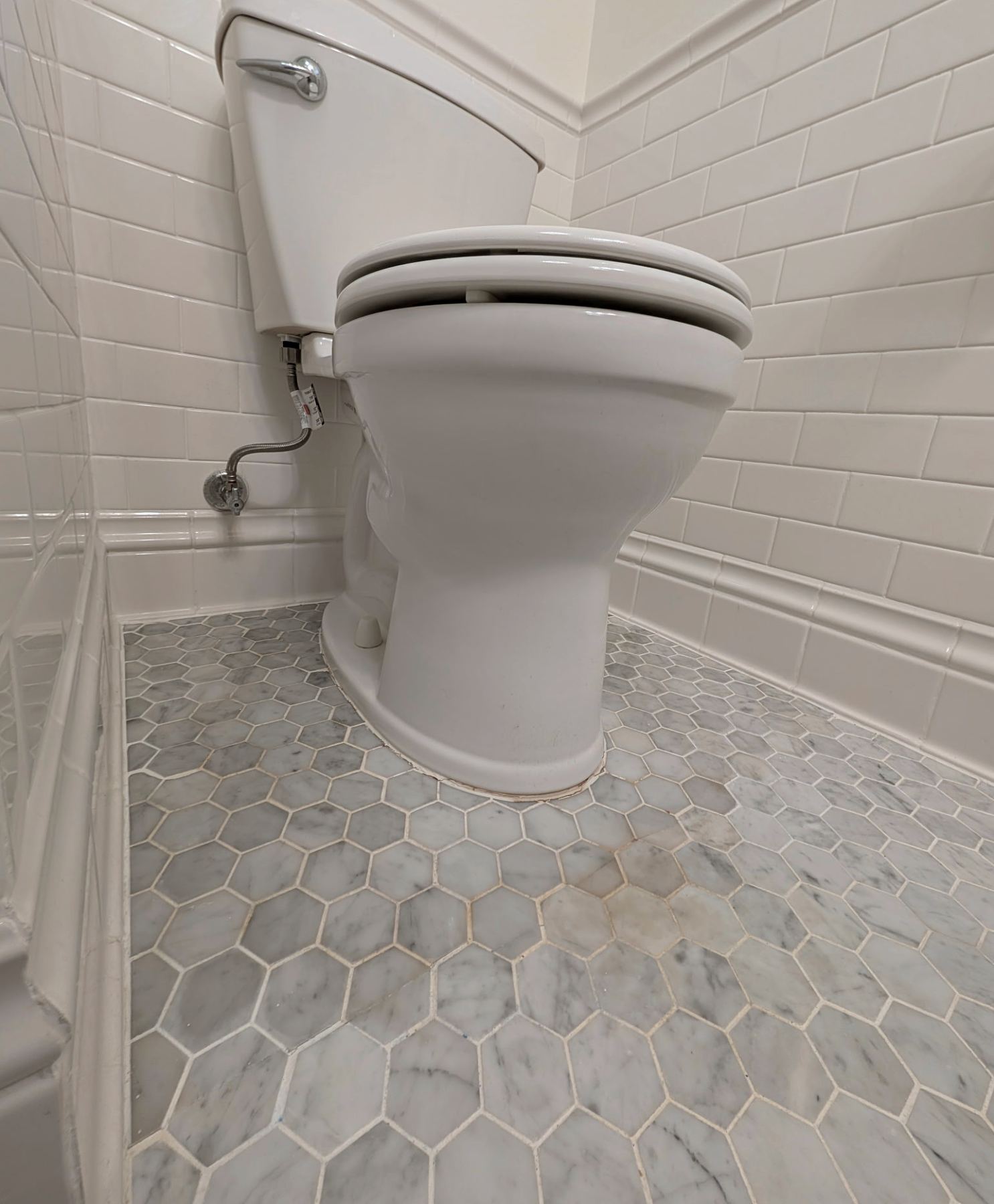 Yellow-brown grout stain and discolored caulk around the base of a toilet on a hex tile floor in a Portland bathroom
