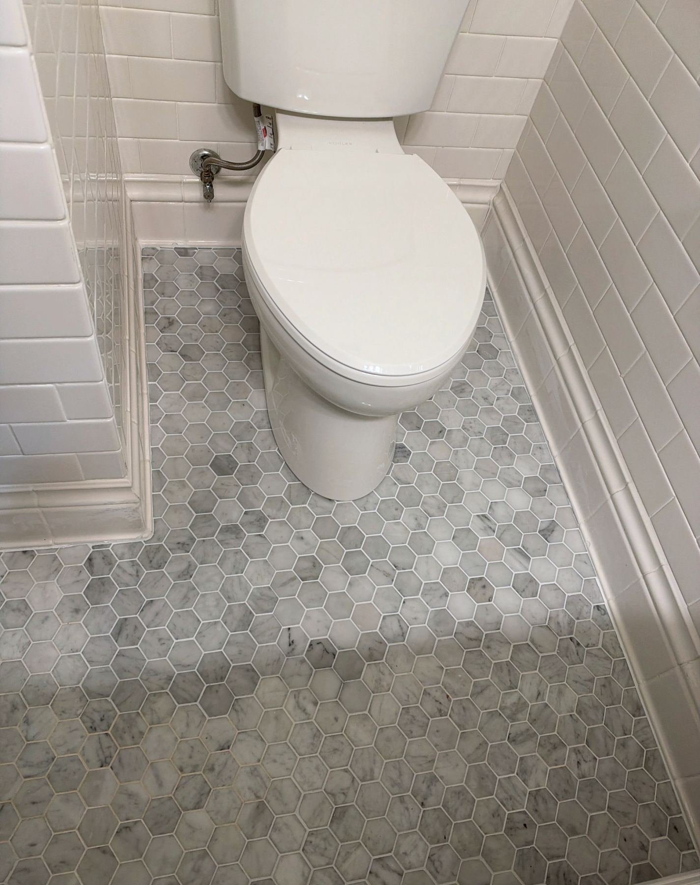 Finished bathroom floor repair with new hex tile matched to the existing floor and the toilet reset in Portland, OR