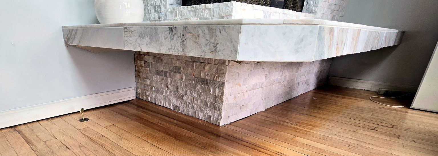 Finished porcelain hearth tile projecting over the hardwood floor