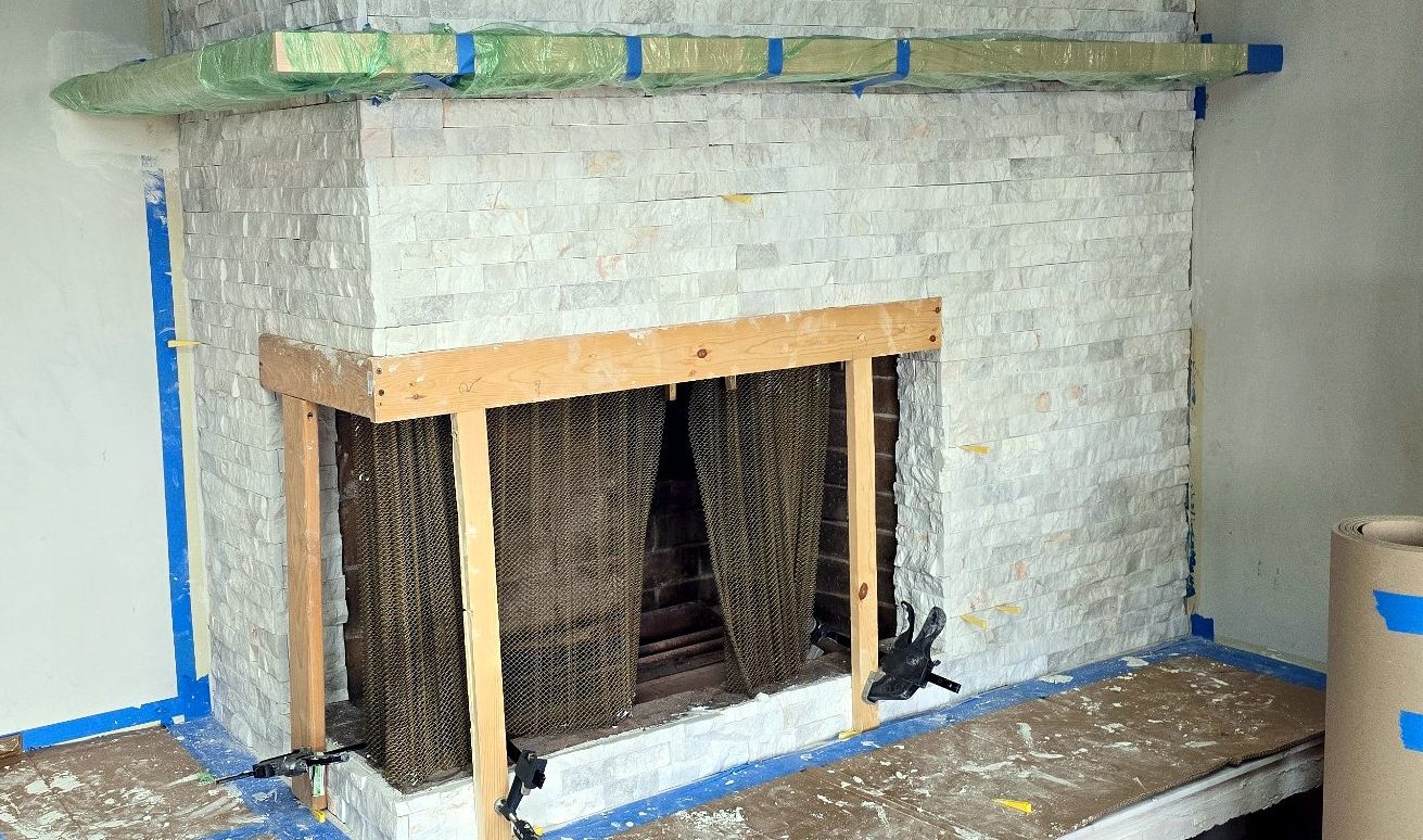 Stone ledger installed with a temporary wood frame protecting the firebox opening
