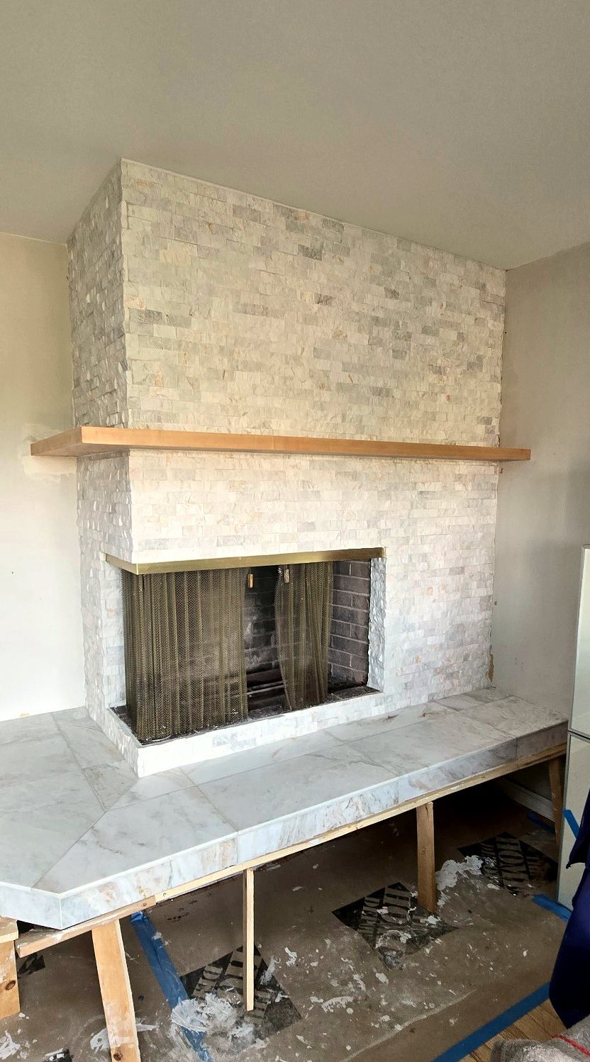 Porcelain tile being installed on the projecting hearth, supported on temporary legs
