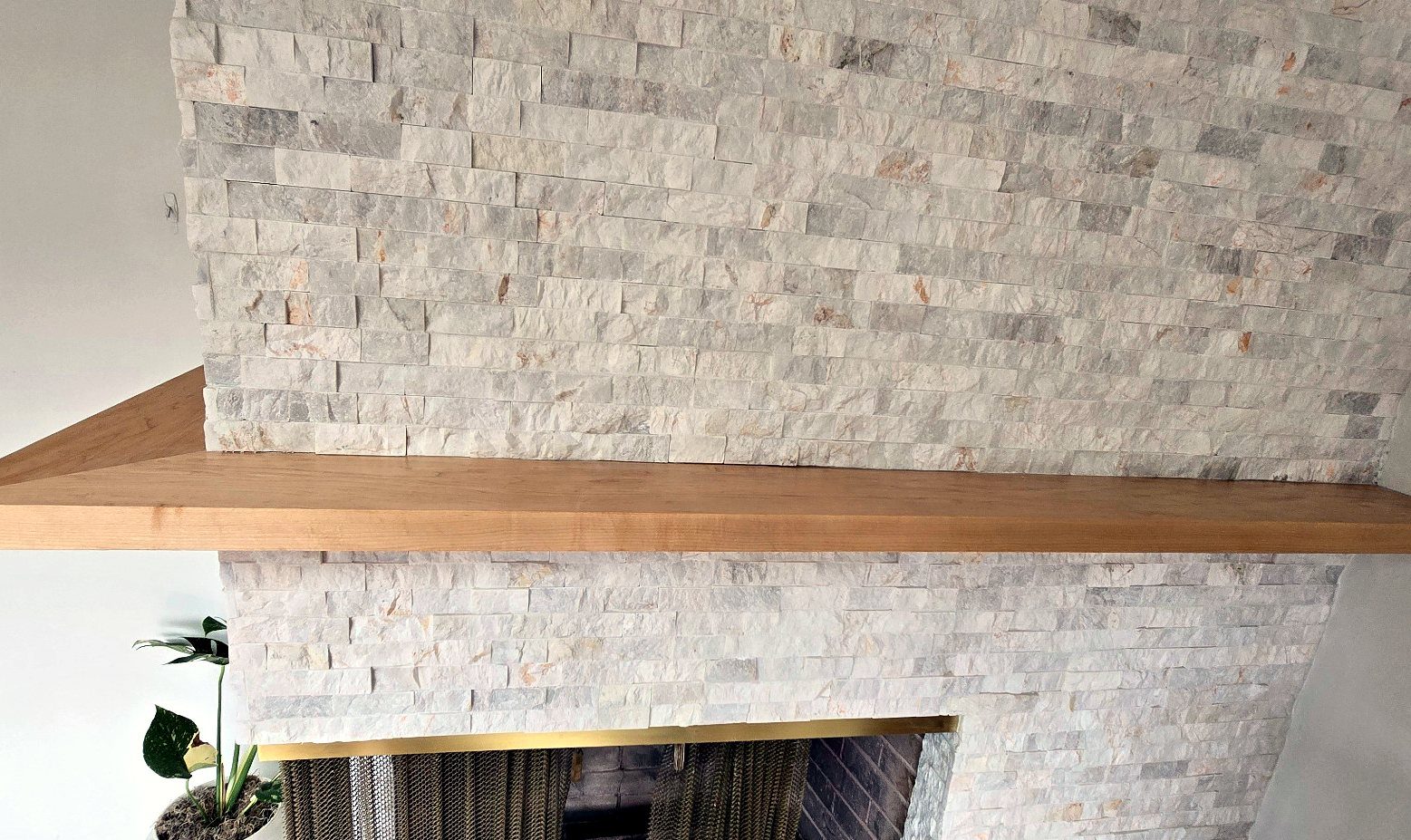 Hardwood shelf running across the stone ledger fireplace face