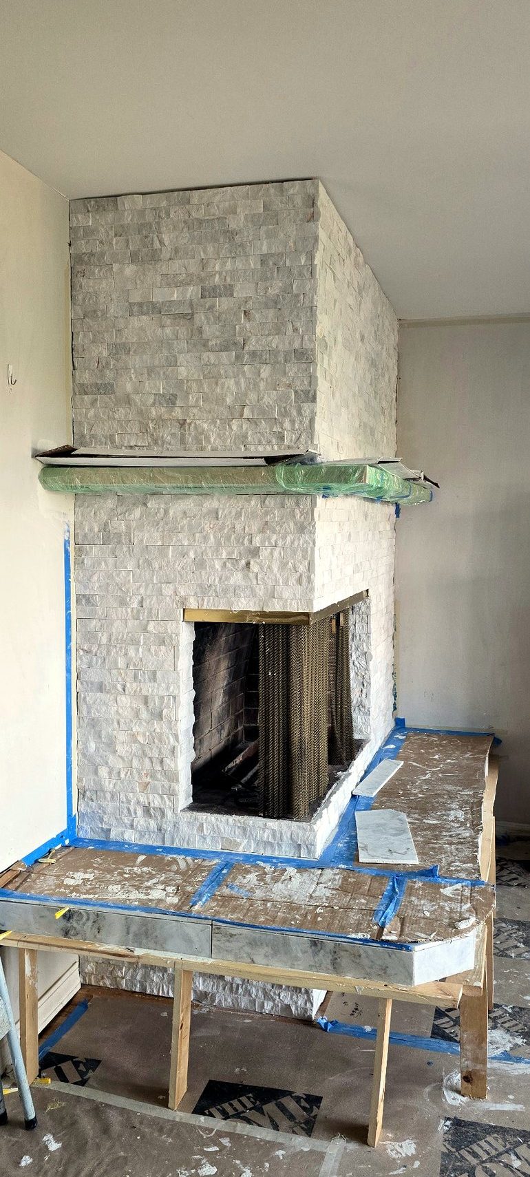 Manufactured stone ledger covering the full fireplace face and chimney breast