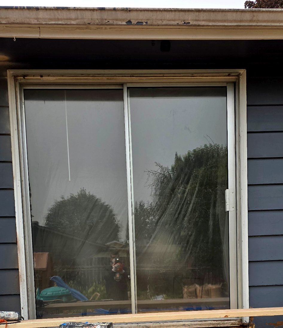 Worn sliding patio door and weathered trim before replacement