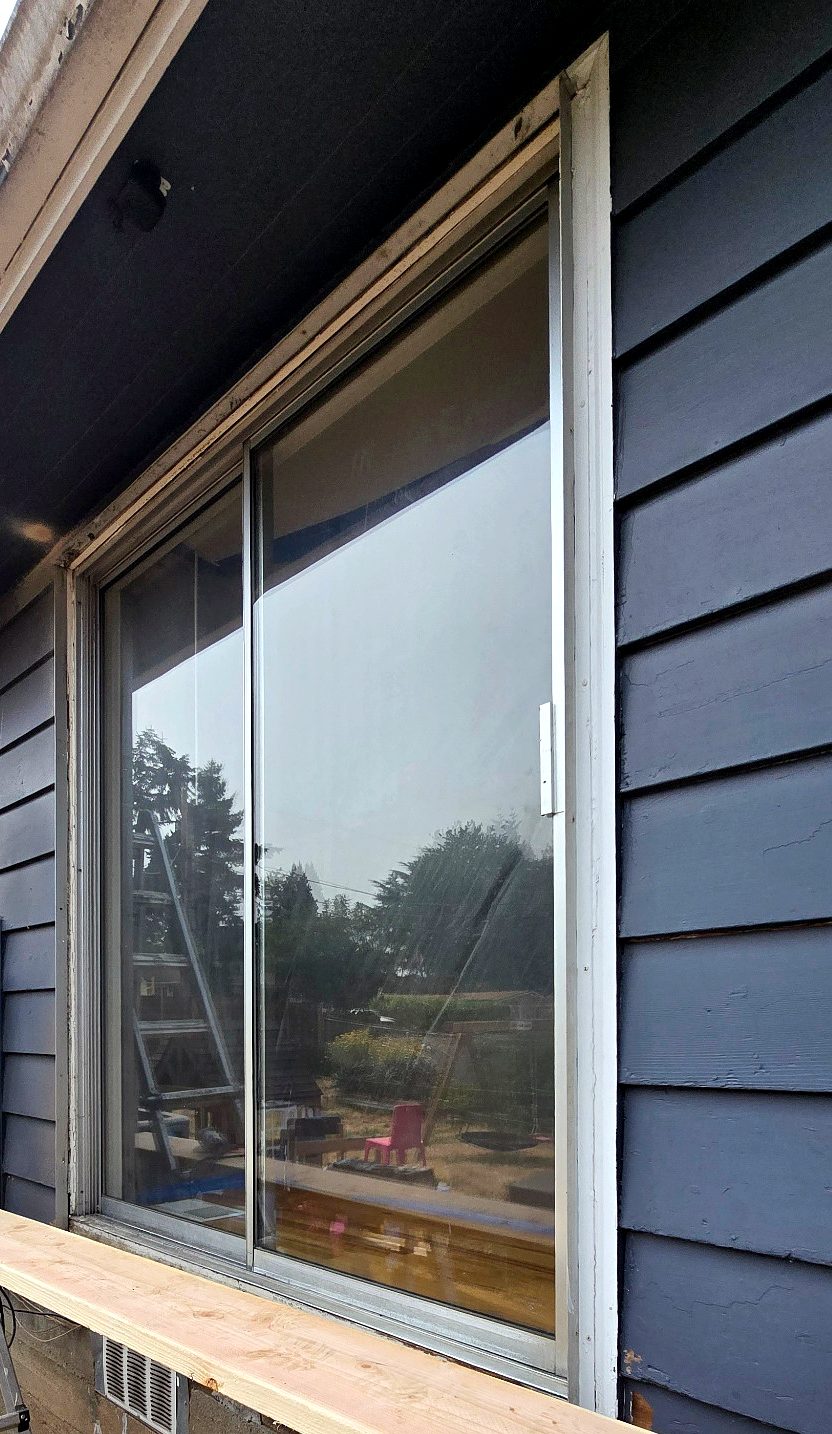 Existing patio door and exterior trim seen along the siding before removal