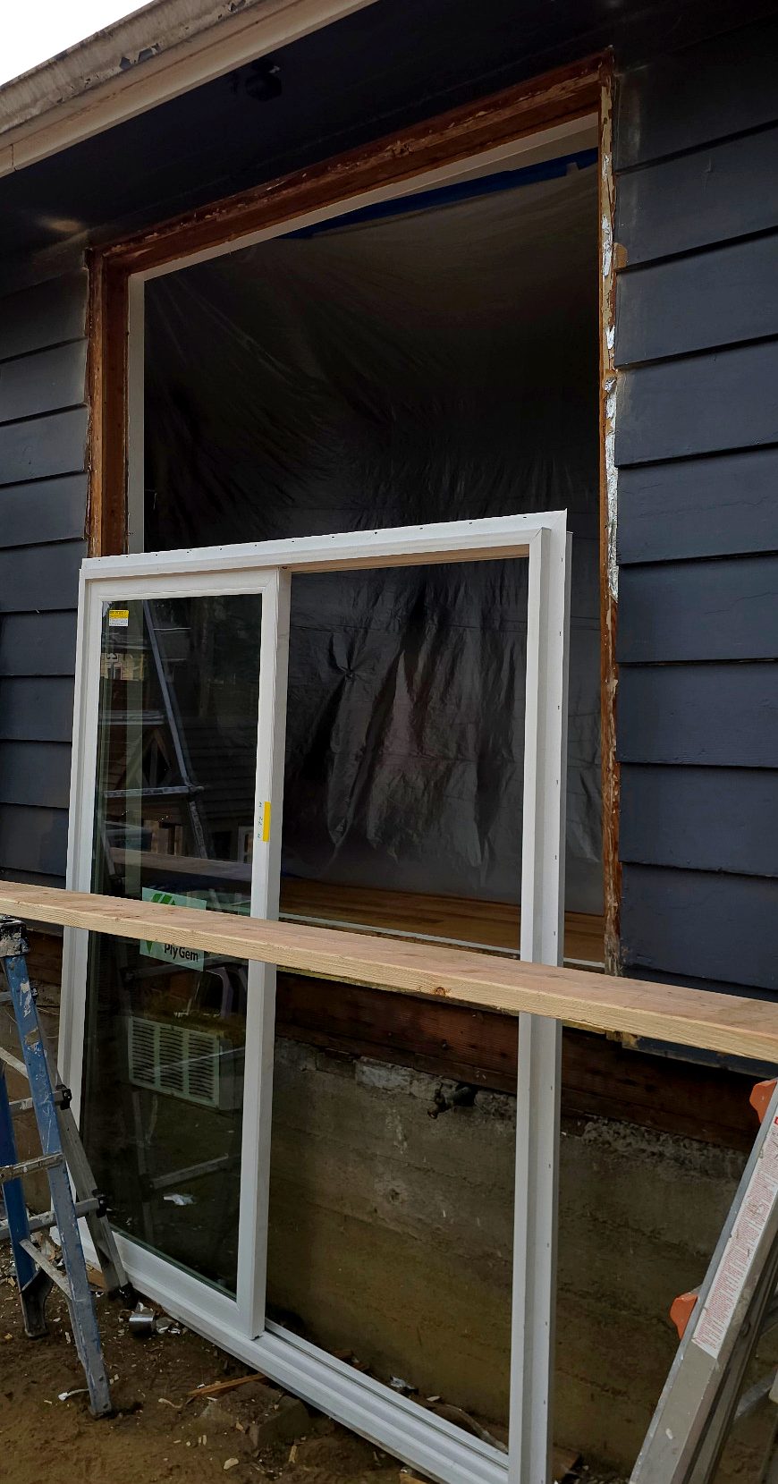 New sliding glass patio door staged outside the prepared opening