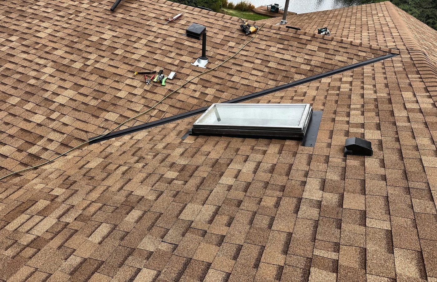 Skylight re-flashed and shingled in with a new pipe jack, box vents and ridge vent on a Desert Tan asphalt roof