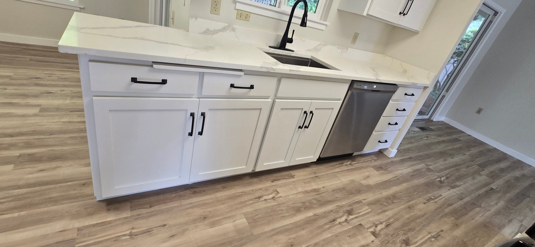 Renovated kitchen with white shaker cabinets, quartz counters and wood-look flooring