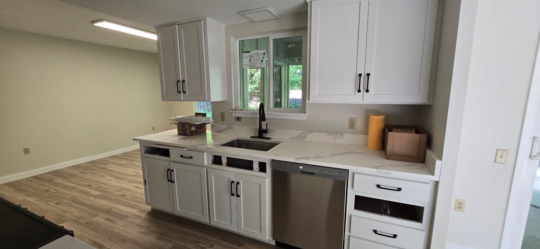Finished kitchen with white cabinets, stainless dishwasher and light quartz counters